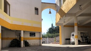 Un patio de hotel con un arco central, una campana y un vehículo estacionado en un área techada.