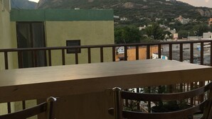 Una terraza con mesa y sillas, con vistas a una montaña y un pueblo.