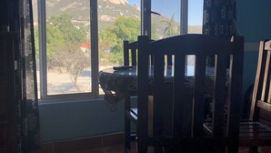 Habitación con un amplio ventanal que ofrece vistas a la montaña. Hay sillas y una mesa de madera en la habitación.