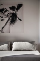 Una cama con dos almohadas y una obra de arte grande en blanco y negro sobre ella.