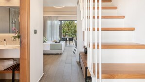 Moderni hotellihuone, jossa on puinen portaikko, suuri peili varustettu kylpyhuone ja näkymä ulos.