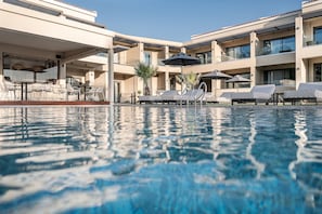 Ett modernt hotell med pool, solstolar och utomhusmöbler.