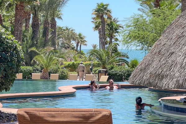 Relax by the serene pool surrounded by lush tropical vegetation and lounge chairs.