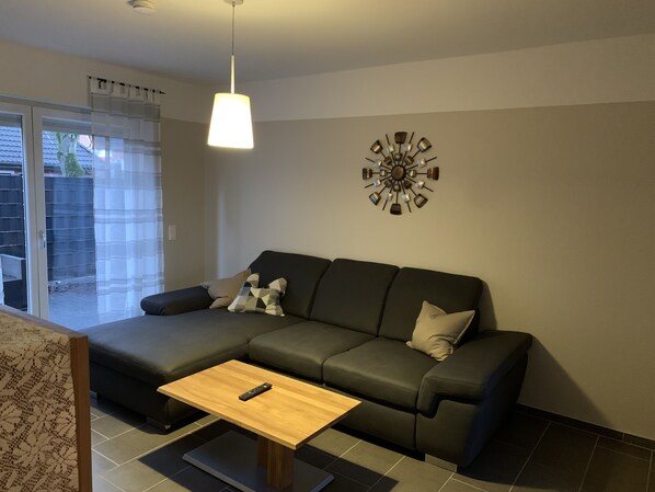 Ein modernes Wohnzimmer mit einem Ecksofa, einem Holztisch und einer Wanddekoration.