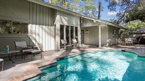 A swimming pool with a tiled edge, surrounded by a wooden deck and outdoor furniture. - Beautiful Home w/ a Short Walk to the Beach! (Hilton Head Island)