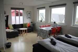 A modern living room with a sofa, a dining table, and a bed.