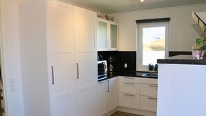 A modern kitchen with white cabinets, a black countertop, and a window providing natural light. - Nordic Inn Thorshavn (Tórshavn)