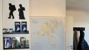 A room with a large map on the wall, a coat rack with jackets, and a door leading to another room. - Nordic Inn Thorshavn (Tórshavn)