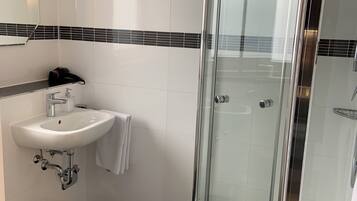 A modern bathroom with a glass-enclosed shower, a white sink, and a toilet.