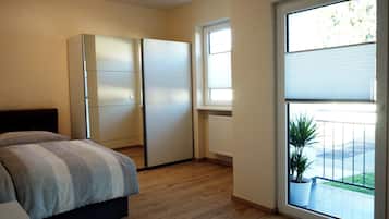 Une chambre à coucher avec un lit, une armoire, une fenêtre avec des stores et une plante en pot.