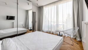 A modern hotel room with two beds, a large mirror, a TV, and a view of the outdoors through sheer curtains. - Blend City Center (Bucharest)
