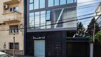 A modern building with a glass facade, a black storefront, and a visible garage door.