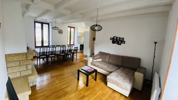A spacious living room with a wooden floor, a sofa, a dining table with chairs, and a fireplace. - Residence daisies N 3 (Mont-Dore)