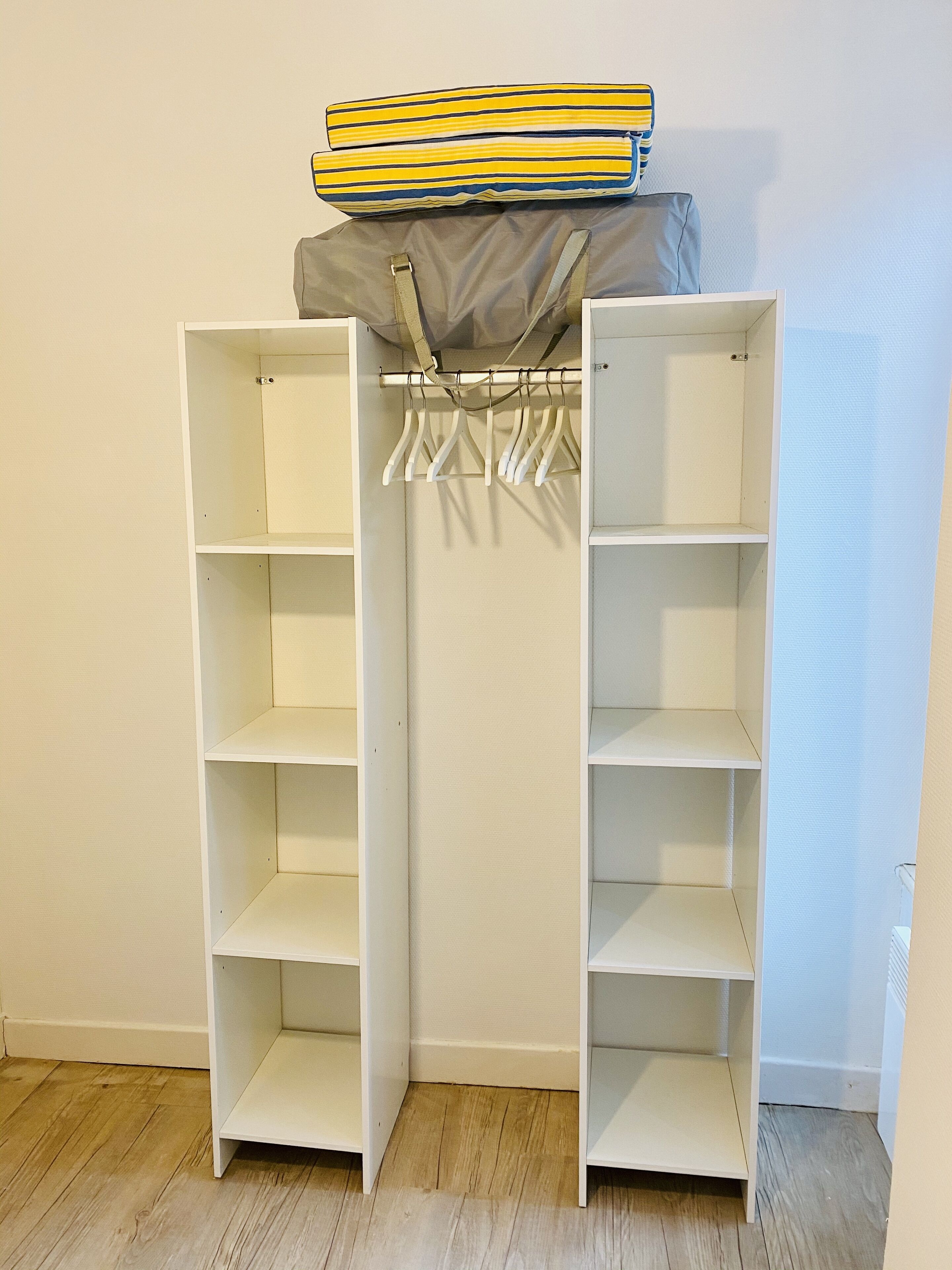 Guarda-roupa branco com portas abertas, com várias prateleiras e cabideiro.