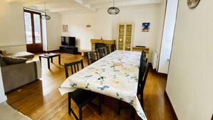 A dining area with a long table, chairs, a television, and a fireplace. - Residence daisies N 3 (Mont-Dore)