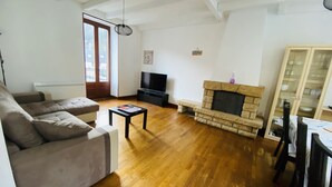 A living room with a sofa, a coffee table, a fireplace, a television, and a dining area. - Residence daisies N 3 (Mont-Dore)