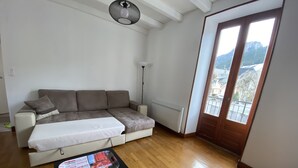 A modern living room with a sectional sofa, a small table, and a view of the outdoors through a large window. - Residence daisies N 3 (Mont-Dore)