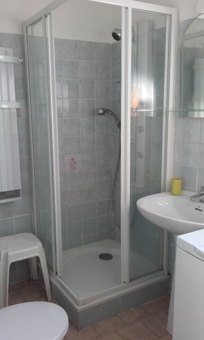 Une salle de bain avec une douche à parois de verre, un lavabo blanc et des toilettes.