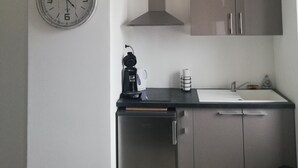 Una cocina compacta con estufa integrada, cafetera y lavamanos.