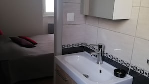 Un baño moderno con un lavamanos blanco, un espejo y un armario de madera.
