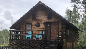 A rustic log cabin with a porch, two blue Adirondack chairs, and a small table. - Wolf Den Cabin is cozy and rustic that overlooks the beautiful aspens trees.   (Lake Dolores)