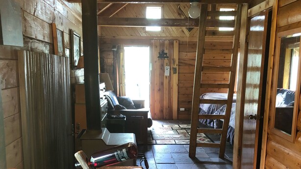 A wooden cabin interior with a round wooden table, two turquoise glass cups, a wooden bench, and a ladder. - Wolf Den Cabin is cozy and rustic that overlooks the beautiful aspens trees.   (Lake Dolores)