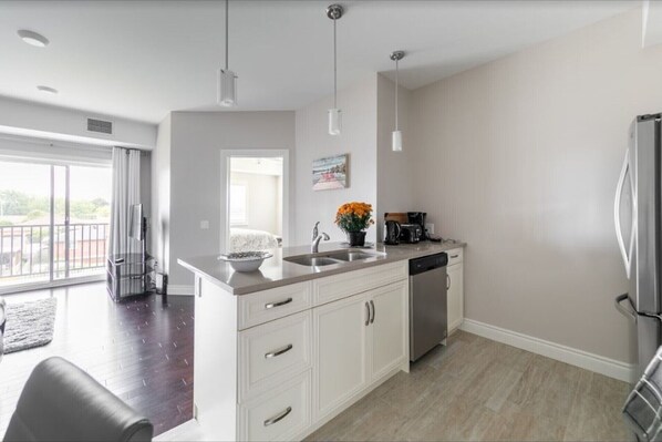A modern kitchen with a large island, stainless steel appliances, and a view to the outside.