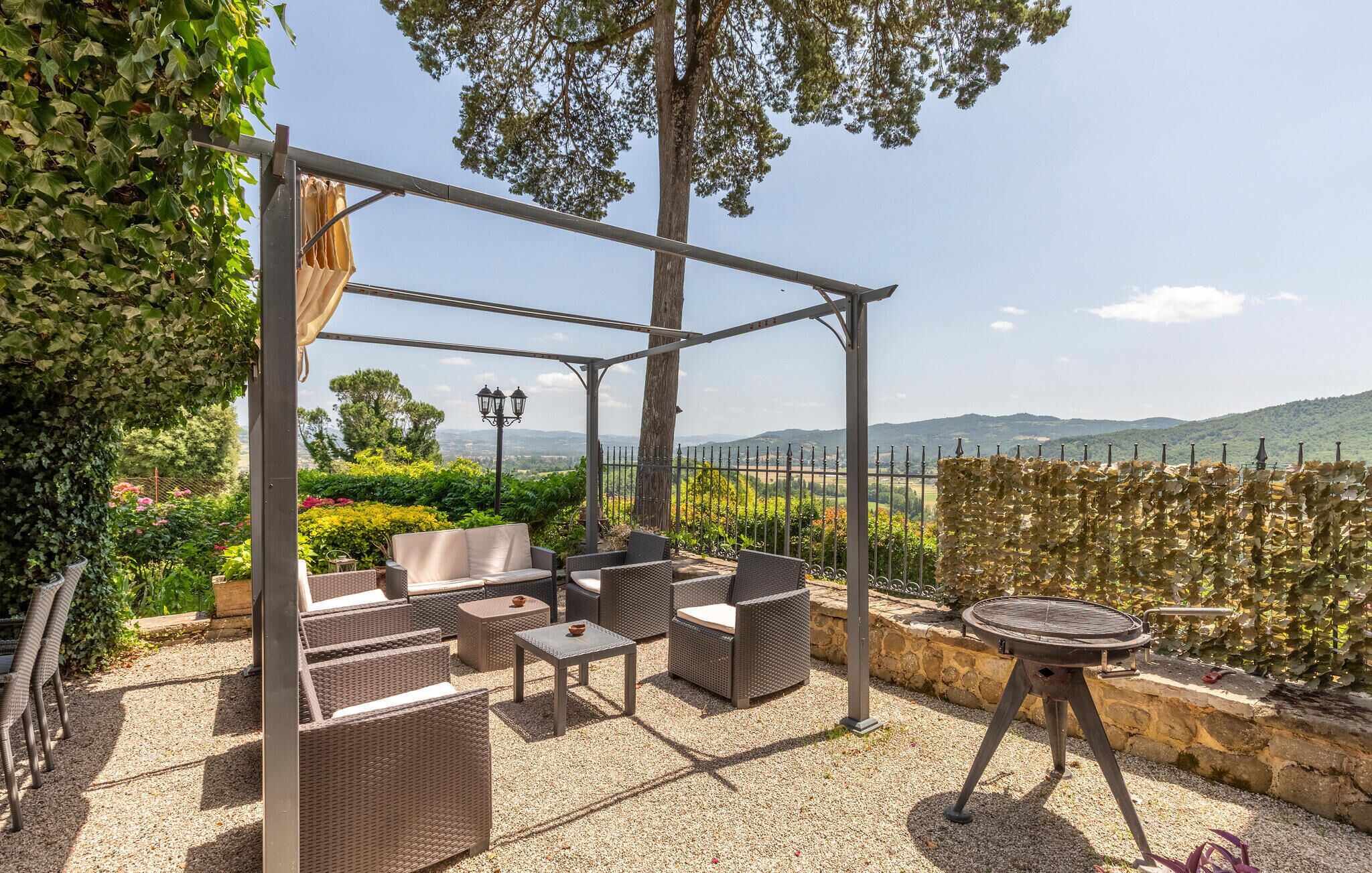 Un patio al aire libre con mobiliario de mimbre, una pérgola y vistas al campo.