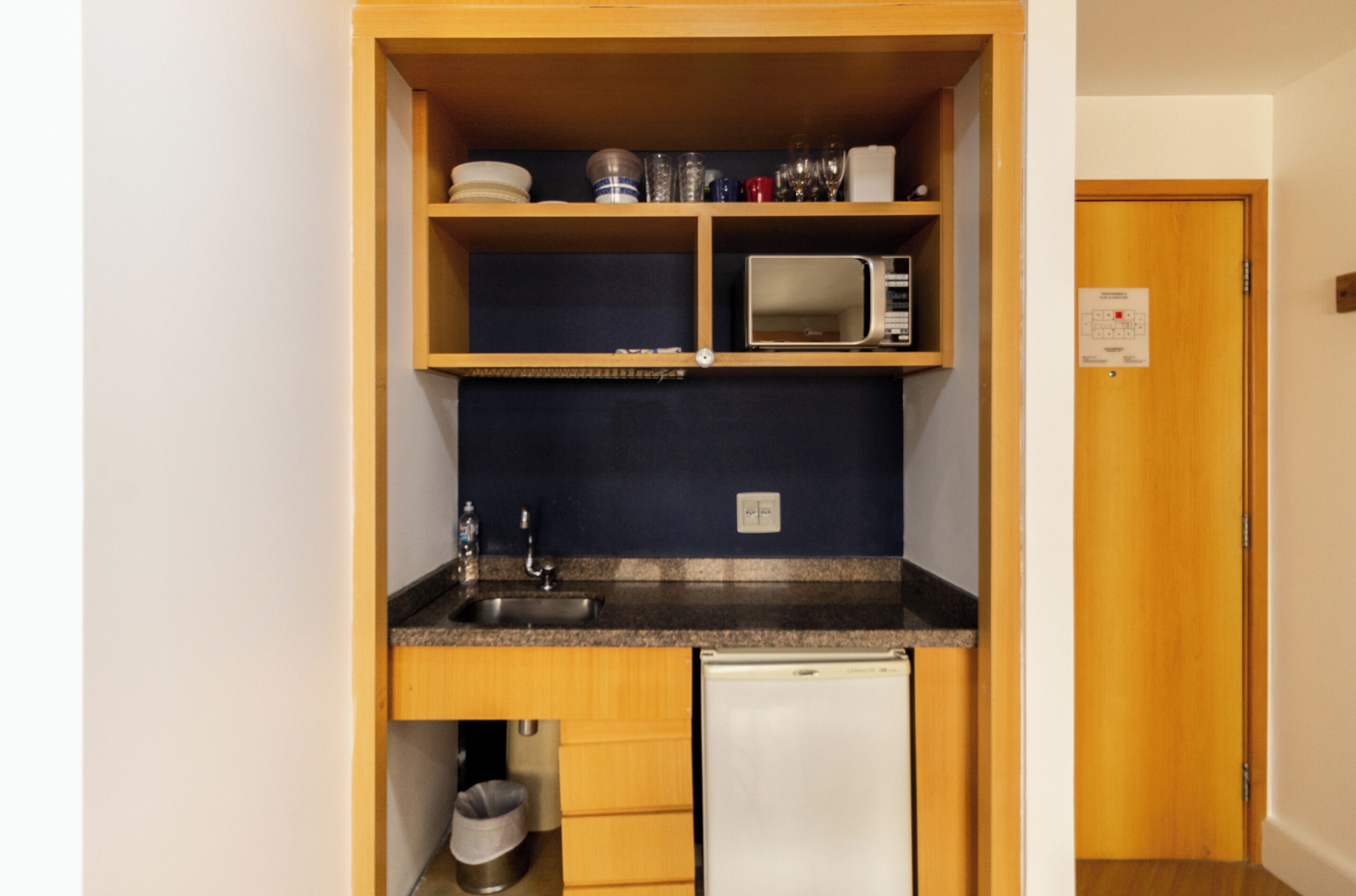Une petite cuisine équipée comprenant un four à micro-ondes, un évier et des placards de rangement.