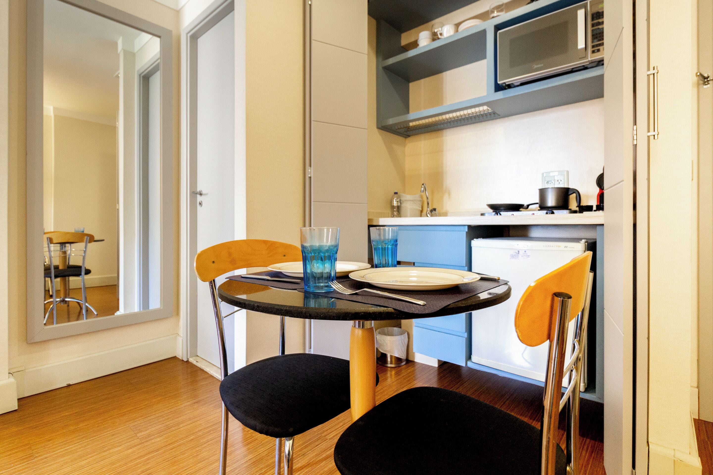 A compact kitchen with a dining area, a microwave, a sink, and a refrigerator.