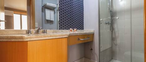 A bathroom with a wooden vanity, a glass shower enclosure, and a tiled floor.
