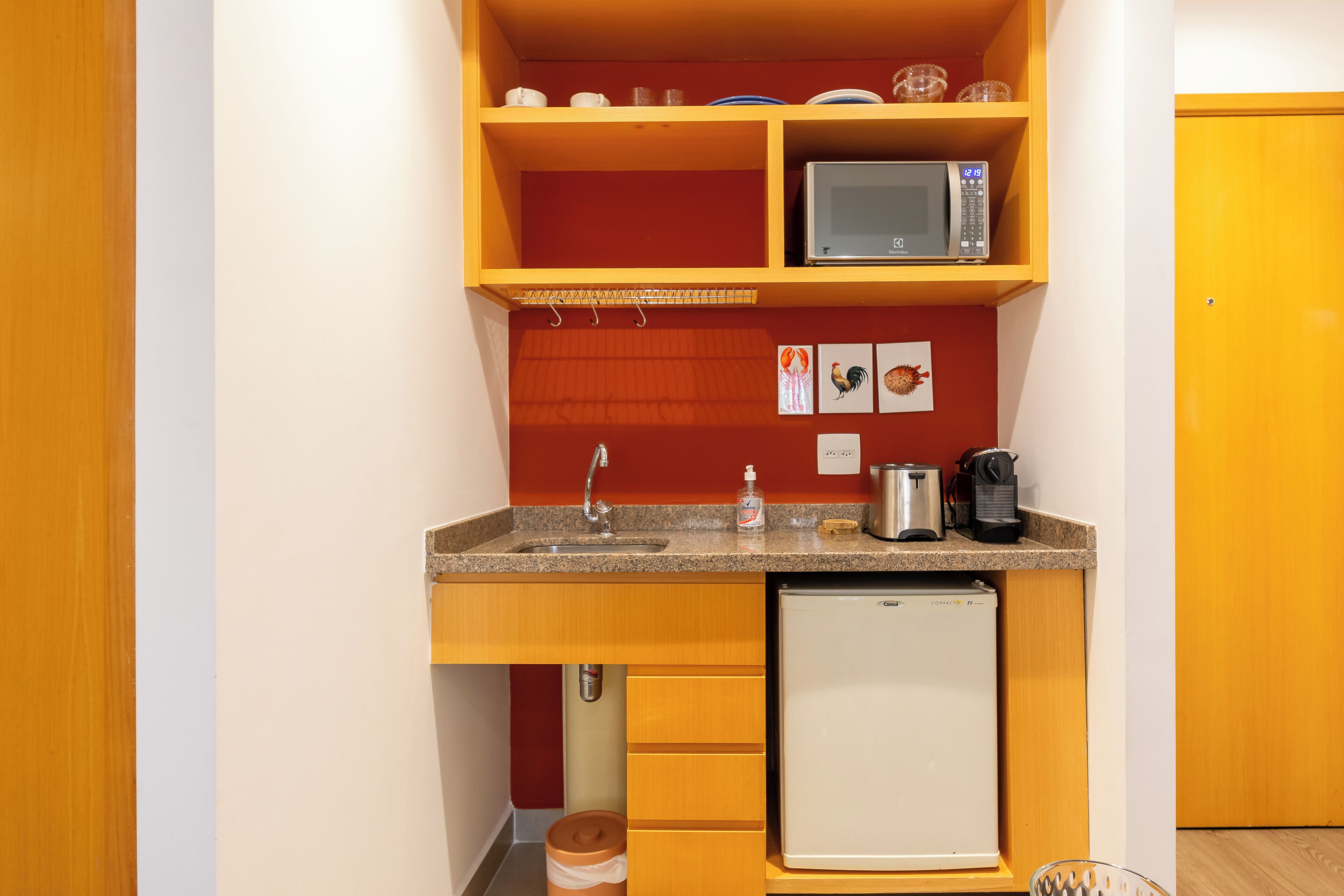 Een kleine keuken met een magnetron, koffiezetapparaat en koelkast.