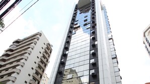 A modern high-rise building with a curved glass facade, a prominent entrance, and a visible logo.