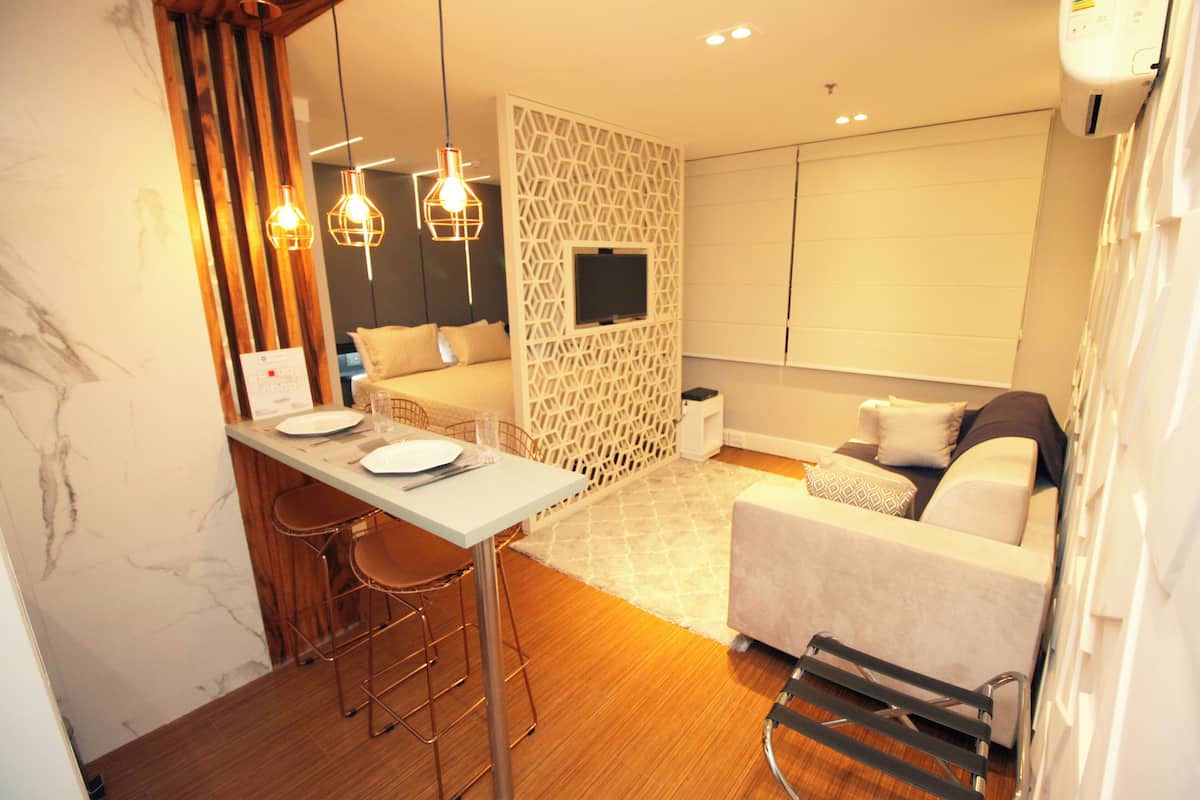 A modern hotel room with a dining area, a sofa, and a TV.