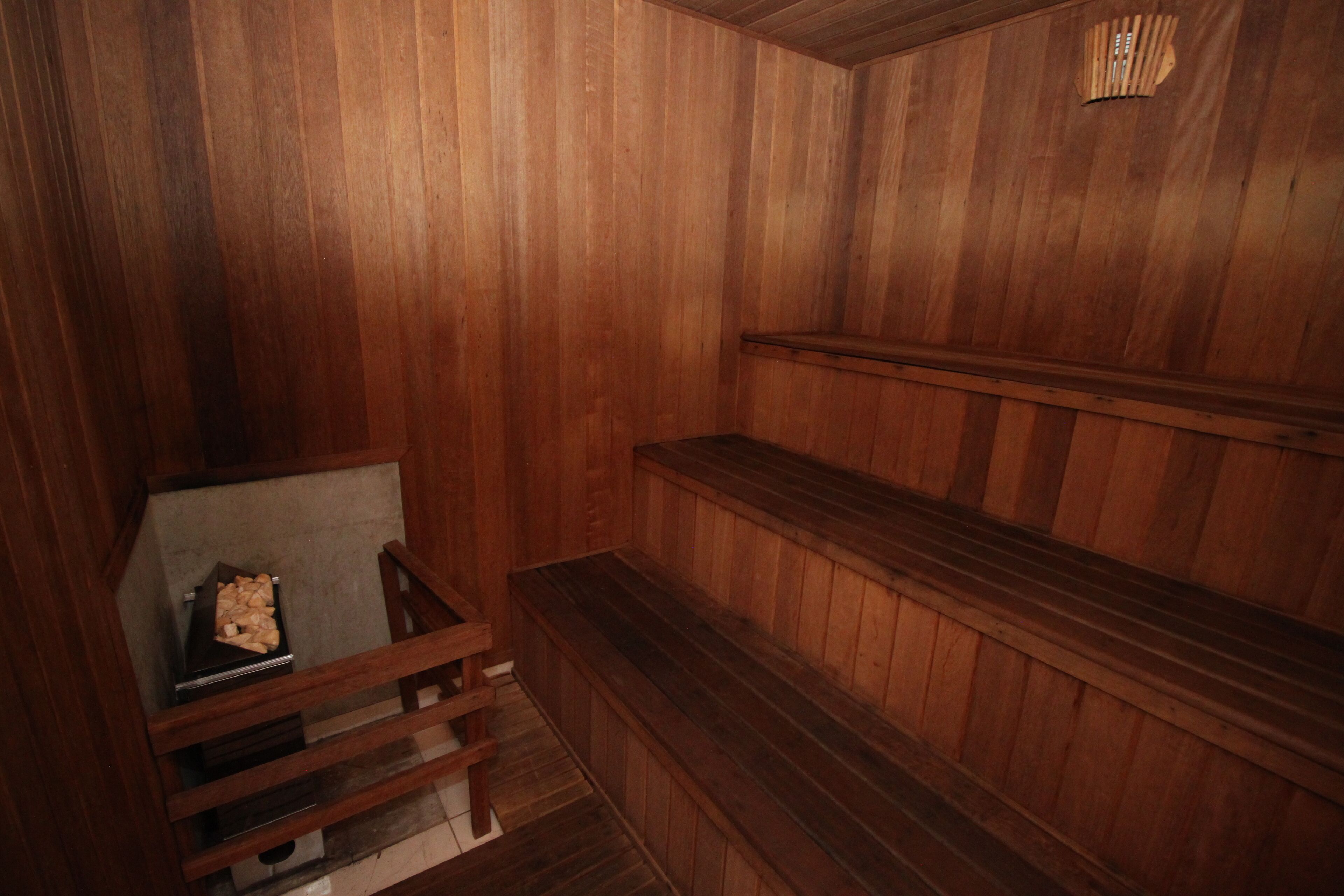 A wooden interior with a bench, a small table with a box, and a wooden shelf.
