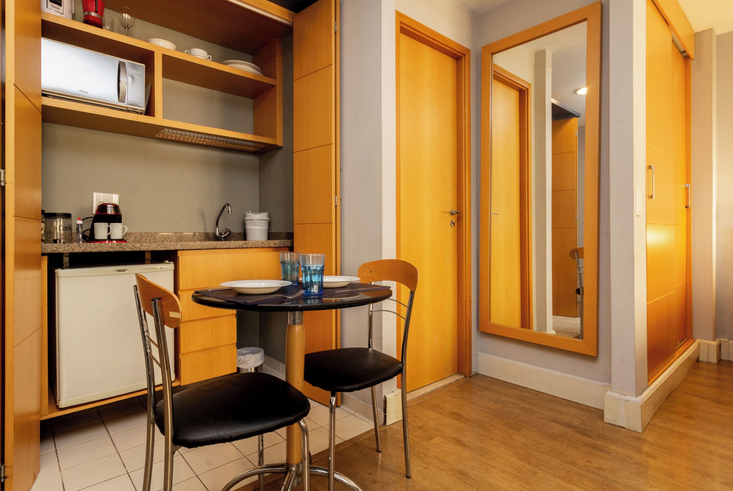 A compact kitchen with a dining table, chairs, and a refrigerator.