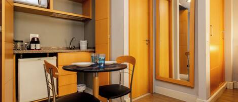 A compact kitchen with a dining table, chairs, and a refrigerator.