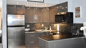Una cocina moderna con electrodomésticos de acero inoxidable, una encimera negra y un letrero con la palabra 'Welcome' sobre el fregadero.