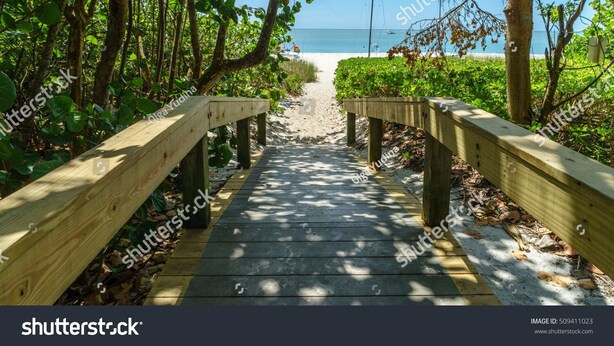 Un sendero de madera que lleva a una playa, con vista despejada al océano.
