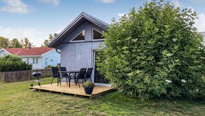 A modern house with a patio, a barbecue grill, and a large bush. - Cozy home in Hagby with kitchen (Hagby)