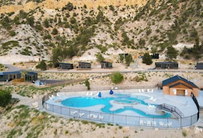 A pool area with lounge chairs, a small building, and a mountainous backdrop. - Zion Glamping Tent w/ A/C & Private Bathroom (Orderville)