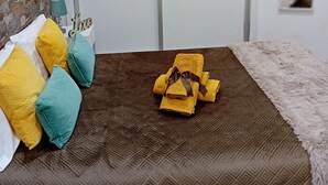 Ein Schlafzimmer mit einer braunen, gemusterten Bettdecke, einer weißen Wand, einer Wand mit Steinakzenten und einer weißen Tür.