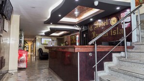 A hotel reception area with a marble counter, a clock, and a staircase leading to an upper floor. - Hotel Bacata Isla (Bucaramanga)
