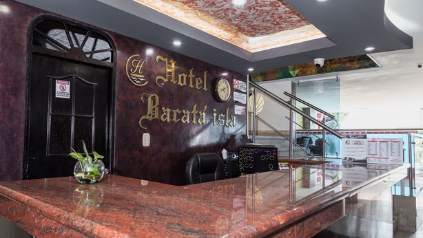 A hotel reception desk with a marble counter, a clock, and a sign indicating the hotel name 'Hotel Barata Island'. - Hotel Bacata Isla (Bucaramanga)