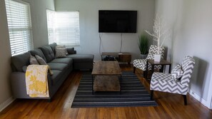 Relax in this stylish living room with a grey sofa, patterned throw blanket, and a flat-screen TV.