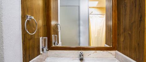 Un baño con lavamanos de mármol, cabina de ducha con paredes de vidrio y un perchero para toallas.