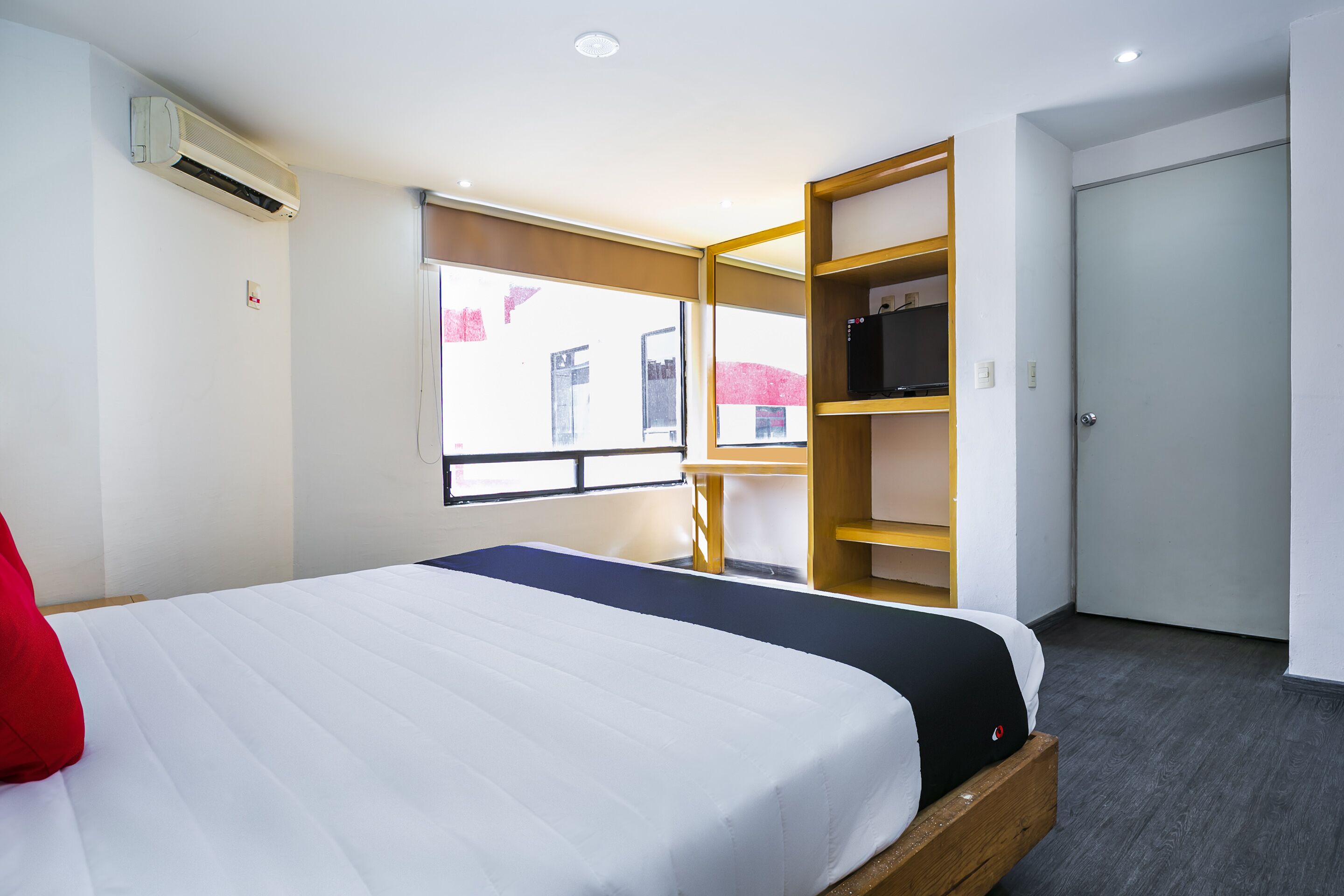 A hotel room with a bed, a wardrobe, a desk, and a window.