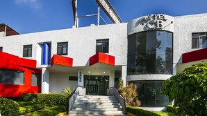 Een hotel met een modern design, met een opvallende trap naar de ingang, een grote glazen gevel en een unieke gebogen constructie boven de entree.