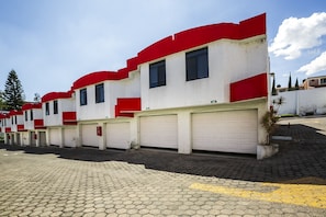 A row of residential buildings with red accents and garage doors. - Capital O Hotel Casa Blanca, Morelia (Morelia)