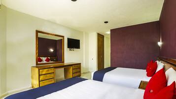 Een hotelkamer met twee bedden, een houten dressoir, een televisie en een spiegel.